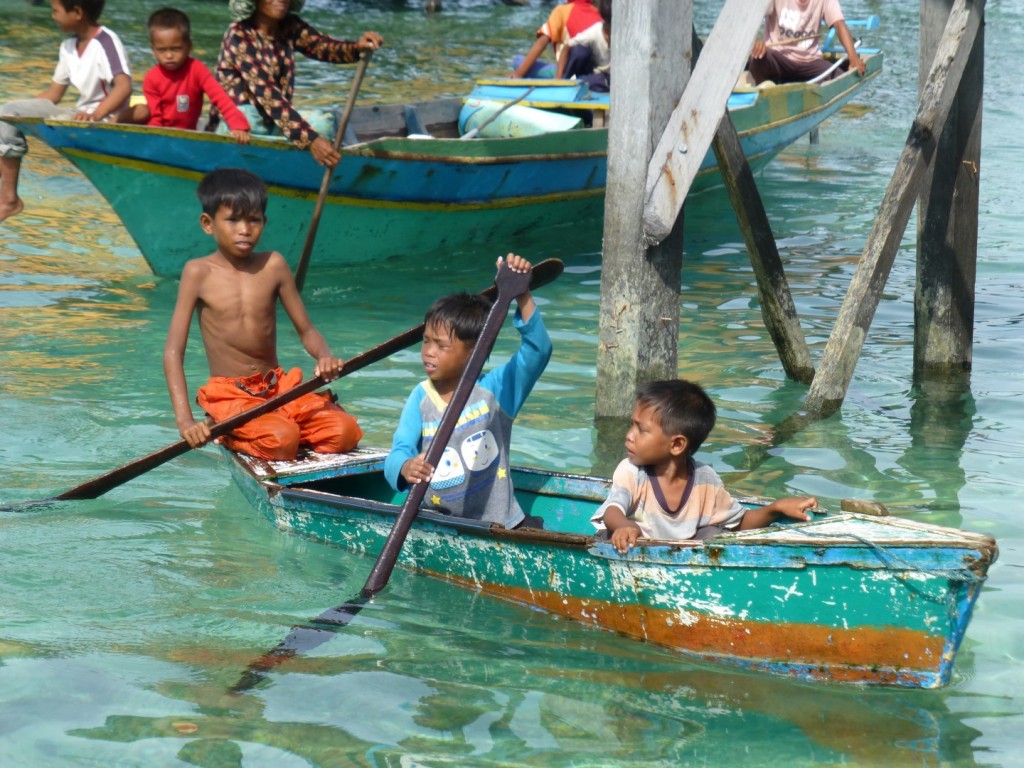 local kids from Mabul paddle over to the huts to beg for money